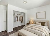 Thumbnail 11 of 13 - A bedroom with a bed, a bench, and a closet with clothes.