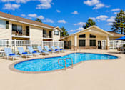 Thumbnail 8 of 22 - A swimming pool surrounded by lounge chairs and a building in the background.