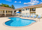 Thumbnail 7 of 22 - A swimming pool in a residential area with a blue umbrella.