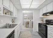 Thumbnail 11 of 19 - A kitchen with white cabinets and a black stove top oven.
