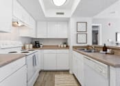 Thumbnail 12 of 21 - A kitchen with white cabinets and a beige countertop.