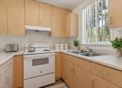 Thumbnail 9 of 16 - A kitchen with wooden cabinets and white appliances.