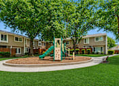 Thumbnail 5 of 16 - A playground with a green slide and brown sandbox in the middle of a grassy area.