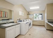 Thumbnail 16 of 16 - A laundry room with a washer and dryer, sink, and a calendar on the wall.