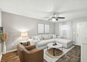 Thumbnail 14 of 23 - A living room with a brown chair, a white couch, and a ceiling fan.