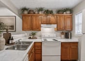 Thumbnail 6 of 14 - A kitchen with wooden cabinets and a white stove top oven.