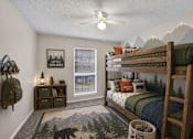 Thumbnail 8 of 14 - A room with a bunk bed, a rug with a bear on it, and a wall hanging that says "Little Explorer".