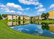 Thumbnail 1 of 24 - A large building complex is reflected in a pond.