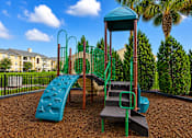 Thumbnail 7 of 24 - A playground with a blue slide and a green tower.