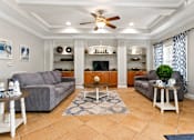 Thumbnail 12 of 24 - A living room with a grey couch, a coffee table, and a ceiling fan.