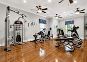 Thumbnail 10 of 24 - A home gym with a treadmill, exercise bike, and weights.