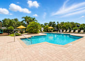 Thumbnail 4 of 24 - A large outdoor swimming pool surrounded by a brick patio.