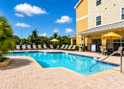 Thumbnail 5 of 24 - A large swimming pool surrounded by lounge chairs and umbrellas.