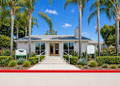 Thumbnail 2 of 12 - A building with a white facade and a red walkway in front.