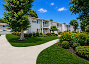 Thumbnail 4 of 12 - A white apartment building with a tree in front of it.