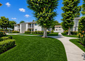 Thumbnail 7 of 12 - A well-maintained lawn leads to a modern apartment building.