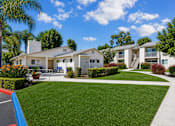 Thumbnail 5 of 12 - A white house with a blue roof and a green lawn in front.