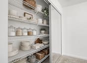 Thumbnail 18 of 25 - A white pantry with shelves full of dishes and containers.