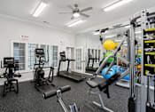 Thumbnail 12 of 25 - A gym with a variety of equipment including a treadmill, weights, and a bench press.