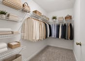 Thumbnail 20 of 25 - A white closet with clothes and towels on shelves.