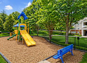 Thumbnail 6 of 25 - A playground with a yellow slide and a blue bench.
