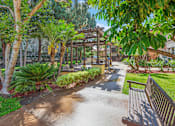 Thumbnail 7 of 16 - A park with a bench and a pathway.