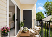 Thumbnail 13 of 24 - A balcony with a chair, table, and potted plants.