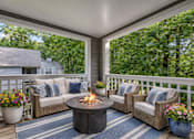 Thumbnail 11 of 26 - Covered patio with fire pit and wicker seating at Delta Crossing Apartments, Charlotte, NC
