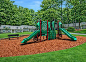 Thumbnail 5 of 22 - A playground with a green slide and a red and green play structure.