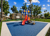 Thumbnail 6 of 21 - A playground with a red slide and a blue and yellow structure.