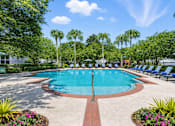 Thumbnail 3 of 21 - A large swimming pool surrounded by trees and lawn chairs.
