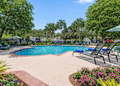 Thumbnail 4 of 21 - A pool surrounded by trees and chairs.