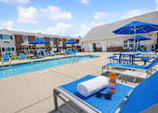 Thumbnail 8 of 14 - A sunny day at the pool with blue loungers and umbrellas.