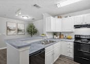 Thumbnail 15 of 22 - A kitchen with a granite countertop and white cabinets.