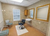 Thumbnail 9 of 20 - A room with a chair, a table, and a mirror.