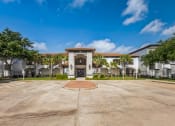 Thumbnail 1 of 26 - a large parking lot in front of a building with palm trees
