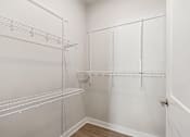 Thumbnail 31 of 36 - A white walk in closet with shelves and hooks.
