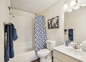 Thumbnail 18 of 24 - A white bathroom with a blue towel hanging on the shower rod.