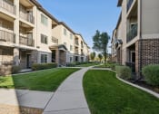 Thumbnail 14 of 31 - a walkway between two apartment buildings on a sunny day