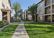 Thumbnail 10 of 31 - a walkway between two apartment buildings with grass and trees