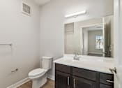 Thumbnail 23 of 36 - A white toilet sits next to a sink in a bathroom.
