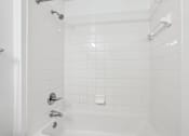 Thumbnail 8 of 20 - A white bathroom with a white tub and white tiles.
