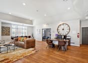 Thumbnail 6 of 14 - A large room with a brown couch and a large clock on the wall.