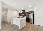 Thumbnail 4 of 36 - A kitchen with a white island and stainless steel appliances.