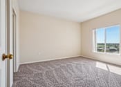 Thumbnail 19 of 36 - A room with a carpeted floor, a door, and a window.