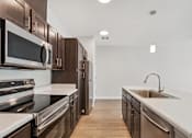Thumbnail 27 of 36 - A modern kitchen with dark wood cabinets and stainless steel appliances.