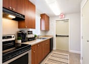 Thumbnail 8 of 9 - A kitchen with a black stove top oven and wooden cabinets.