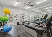 Thumbnail 11 of 20 - A gym with a treadmill, exercise balls, and other equipment.
