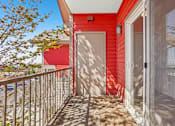Thumbnail 32 of 36 - A red house with a white door and a balcony.