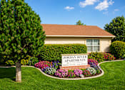 Thumbnail 1 of 20 - A well-maintained lawn surrounds a building with a sign that reads "Jordan River Apartments.".